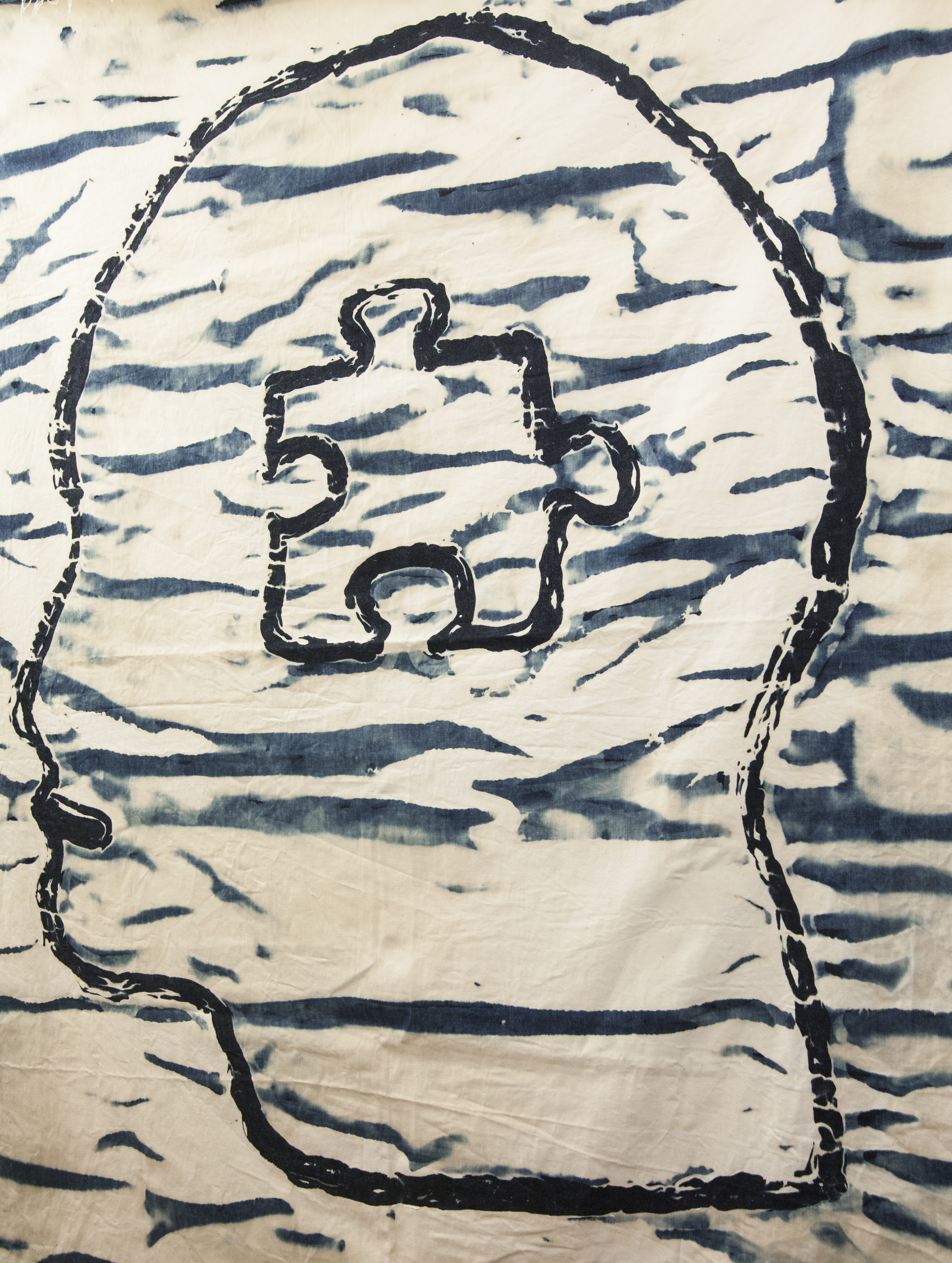 A large patch of bleached denim depicting a face with a puzzle piece in it